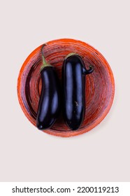 Ugly Eggplant With Nose And Normal Eggplant On Orange Plate. Funny, Abnormal Vegetable, Ugly Produce Or Food Waste Concept.