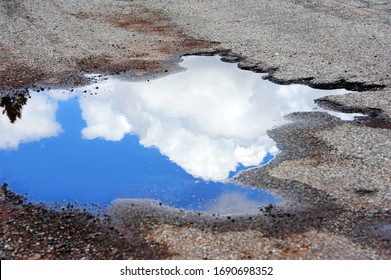 Ugly pothole is beautiful with a blue sky reflection and white fluffy clouds.  Pothole is in the Santa Fe National Forest in New Mexico.