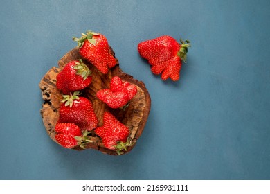 Ugly strawberries, top view, selective focus. Unusual organic strawberries. Deformed fruits strange shape. Concept - Reduce organic food waste. Using in cooking imperfect products.