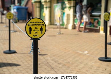 UK, Brighton, 22/6/2020 - A Shallow Depth Of Field Shot Of A Social Distancing Sign Outside A Shop With People In The Background