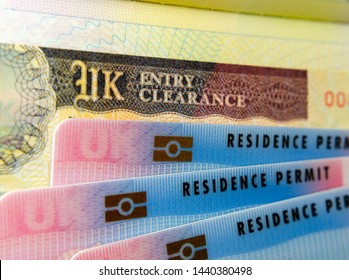 UK BRP (Biometrical Residence Permit) Cards For Tier 2 Work Visa Placed On Top Of UK Entry Clearance Vignette Sticker In The Passport. Close Up Photo. 