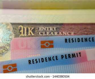 UK BRP (Biometrical Residence Permit) Cards For Tier 2 Work Visa Placed On Top Of UK Entry Clearance Vignette Sticker In The Passport. Close Up Photo. 