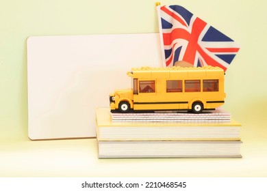 UK Flag Near White Board, Toy School Bus On Books. The Concept Of Learning English, Language School, Development, Education, Foreign Language Courses. Day Light.