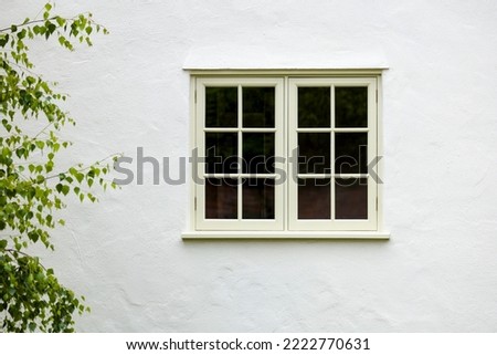 UK house exterior with wooden casement window and white wall rendering