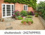 UK house and garden with patio and French doors. Cottage or courtyard garden (backyard) with gravel and York stone paving
