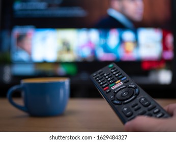 UK, Jan 2020: Netflix Remote Control With TV Behind In Evening With Netflix Menu