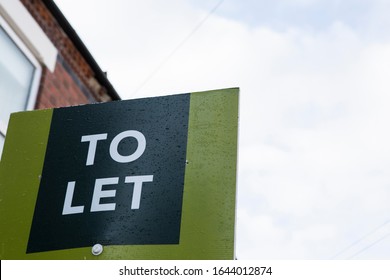 UK To Let Sign With Space To Right Of Image. England Housing Market Buy To Let Lettings Sign In Front Of A Red Brick Terrace House Rental Property With Some Sky 