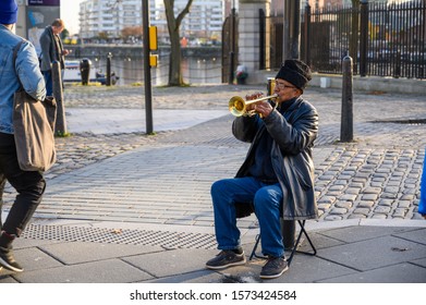 UK, LIVERPOOL - NOVEMBER 10, 2019: A Busker Playing A Trumpet On A Cold But Sunny Day