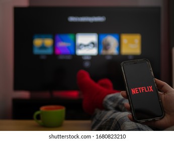 UK, March 2020: TV Television Netflix on phone and tv with feet up comfy