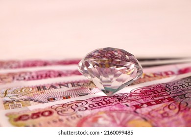 UK Money Bills With Large Diamond Close Up. Big Amount Of United Kingdom Pounds And Huge Transparent Gem On Table. Business And Jewellery Concept For England