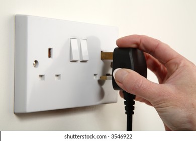 UK Plug About To Be Plugged Into A White Wall Socket