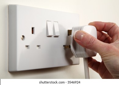 UK Plug About To Be Plugged Into A White Wall Socket