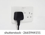 UK plug socket and plug on a white wall