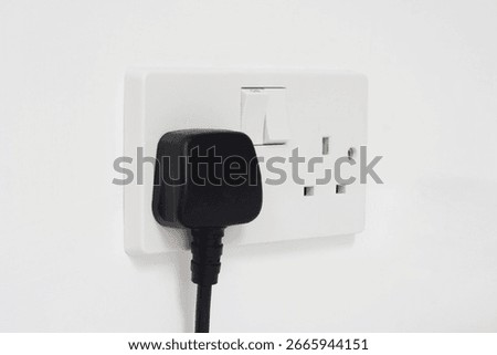 UK plug socket and plug on a white wall