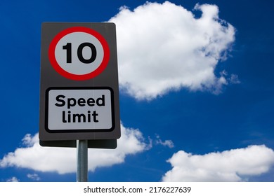UK road sign 10 mph speed limit against a blue cloudy sky.