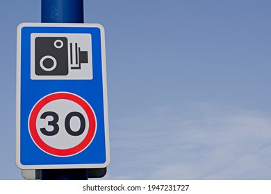 UK Road Sign Speed Camera And 30 Mph Speed Limit Against A Blue Cloudy Sky 