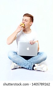 UKRAINE KHERSON APRIL 14, 2019 The Guy Is Sitting And Holding A Laptop And Eating An Apple