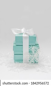 Ukraine, Kiev - December 17, 2016: Tower Of Branded Tiffany Boxes Tied With Silk Ribbon, Surrounded By Artificial Snowflakes On A White Background.