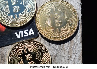 Ukraine, Kremenchug - March, 2019: Golden Bitcoins On Visa Card And Wooden Background