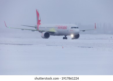 Ukraine, Kyiv - February 12, 2021: Poor visibility, fog. Passenger plane A6-ATD AIR ARABIA AIRBUS A321NEO. Winter at the airport. Snow at the runway.