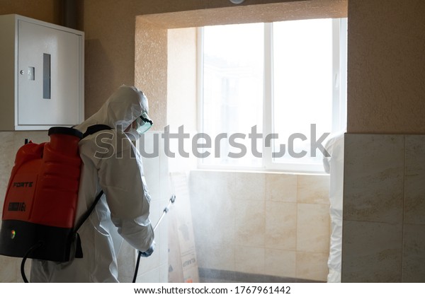 UKRAINE, KYIV - May 20, 2020: Man in a white
protective suit and mask is sanitizing interior surfaces inside
buildings while the coronavirus epidemic for infection prevention
and control of
epidemic.