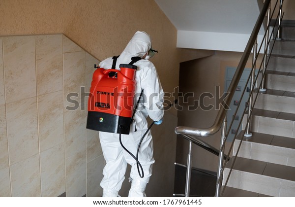 UKRAINE, KYIV - May 20, 2020: Man in a white
protective suit and mask is sanitizing interior surfaces inside
buildings while the coronavirus epidemic for infection prevention
and control of
epidemic.