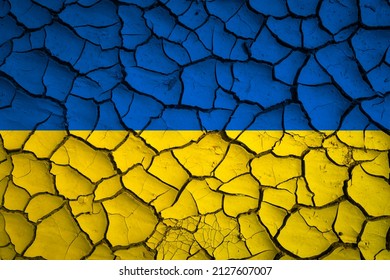 Ukraine national blue and yellow flag on a mud texture of dry cracks on the ground