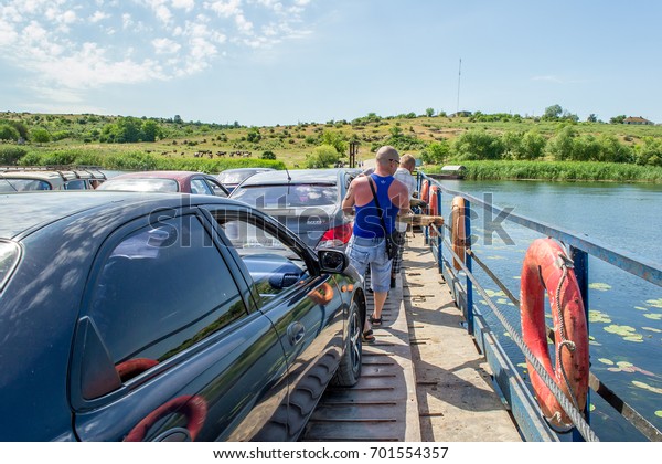 Ukraine,\
Southern Bug River - 4 June 2017: Ferry crossing. The ferry moves\
with the help of a man\'s muscular strength. Repels from the steel\
cable. Such a ferry is unique in\
Ukraine.
