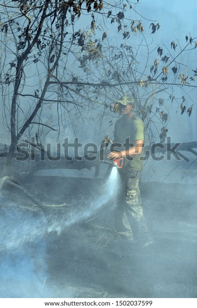 Ukrainian fireman team in the forest. A lot of\
forest wildfires at dry september. September 10, 2019. Near Kiev,\
Ukraine.