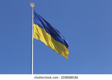 Ukrainian Flag Against Blue Sky With A Golden Trident On The Top Of The Flag Mast.