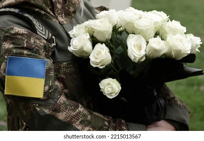 Ukrainian flag on military uniform. Soldier holds flowers. A funerals of Ukrainian servicemen.  - Shutterstock ID 2215013567