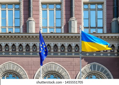 Ukrainian flag waving on a flagpole. Next to it there is an European Union Flag. Moderate wind swings the flags nicely. Background is a red brick building. - Shutterstock ID 1455551705