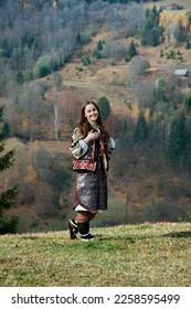 A Ukrainian girl in a Hutsul national costume stands against the background of a mountain landscape on a sunny autumn day. - Shutterstock ID 2258595499