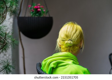 A Ukrainian Girl With Yellow Hair In A Yellow Hoodie Sits In A Wicker Outdoor Chair On The Terrace In The Evening