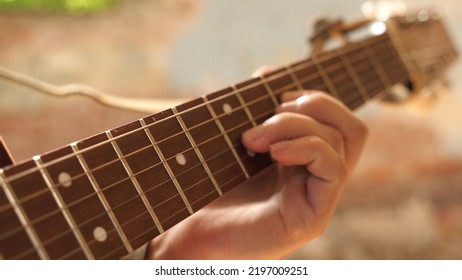 Ukrainian military man in a camouflage uniform plays an acoustic guitar, strumming chords. close-up, rest after battle, music in war. military hobby. an infantryman writes a song after being on duty