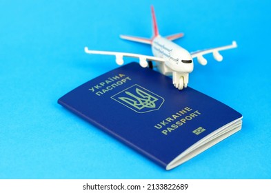 Ukrainian Passport And A Toy Plastic Plane On A Blue Background. Departure Of Ukrainians Abroad