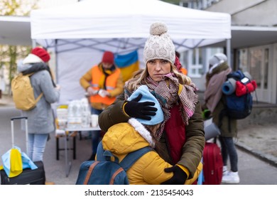 Ukrainian refugee mother with child crossing border and looking at camera.