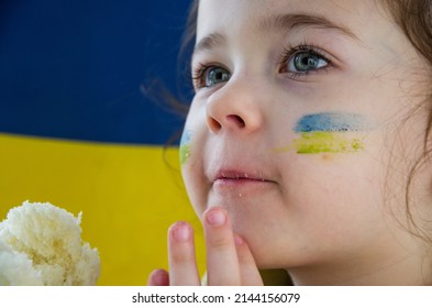 Ukrainian Refugees. Child With Ukrainian Flag. Children Against War. Stop War. Russian-Ukrainian War. War In Ukraine. UNICEF. Peace Concept. Ukrainian Flag On A Child's Face. Child With Bread