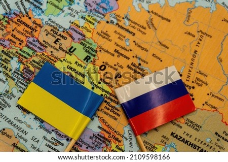 The Ukrainian and Russian flags are placed on a map of Europe.selective focus on the smaller flags top. International situation theme