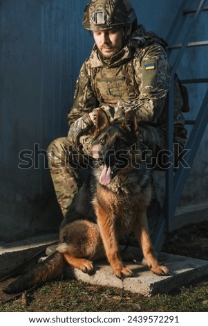 Ukrainian soldier with German shepherd dog sitting outdoors