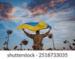 Ukrainian soldier holds Ukrainian flag in sunflower field. Remembrance Day concept for fallen soldiers