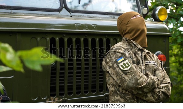 Ukrainian soldier rests while sitting on the
bumper of a military truck  Patch on the uniform with the
inscription 