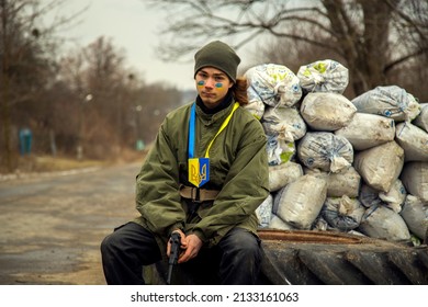 Ukrainian teenage boy with a weapon at a checkpoint. A Ukrainian patriot guards the entrance to the village.