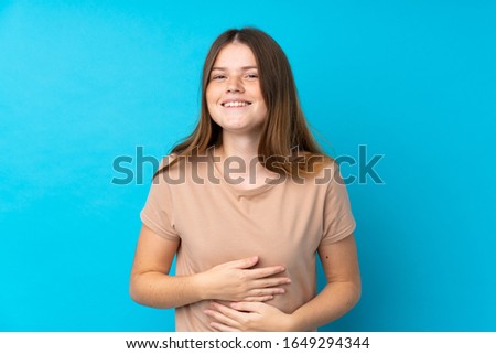Ukrainian teenager girl over isolated blue background smiling a lot