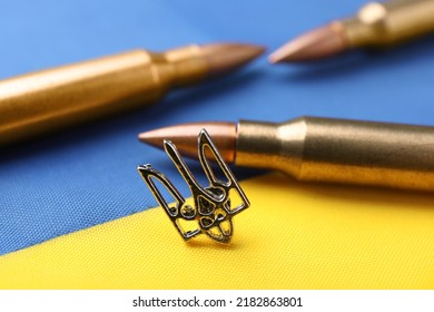 Ukrainian trident and bullets on national flag of Ukraine, closeup - Shutterstock ID 2182863801