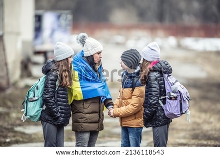 Ukrainian woman fleeing the conflict with children reassures her three kids that everything will be okay.