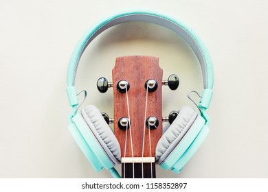 Ukulele with green headphones on white background and added color filter effect for musical instrument and relaxation concept