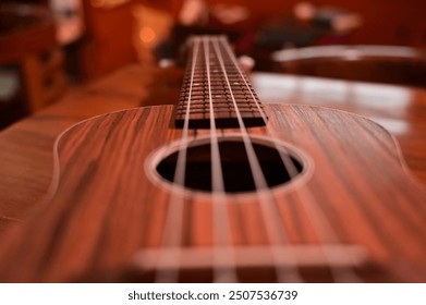 UKULELE WITH SELECTIVE FOCUS WITH TABLE BACKGROUND.
