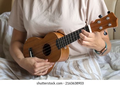 ukulele in women's hands, learning to play the ukulele close-up, Girl playing the ukulele, selective focus.