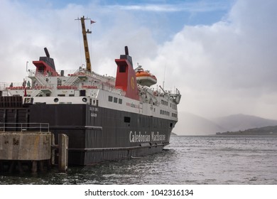 Ullapool, Scotland - June 8, 2012: Black White And Red Ferry Boat Named Caledonian Macbrayne Docked In Harbor Of Ullapool On Loch Broom. Fog Over Water, Hills And Cloudscape In Back.